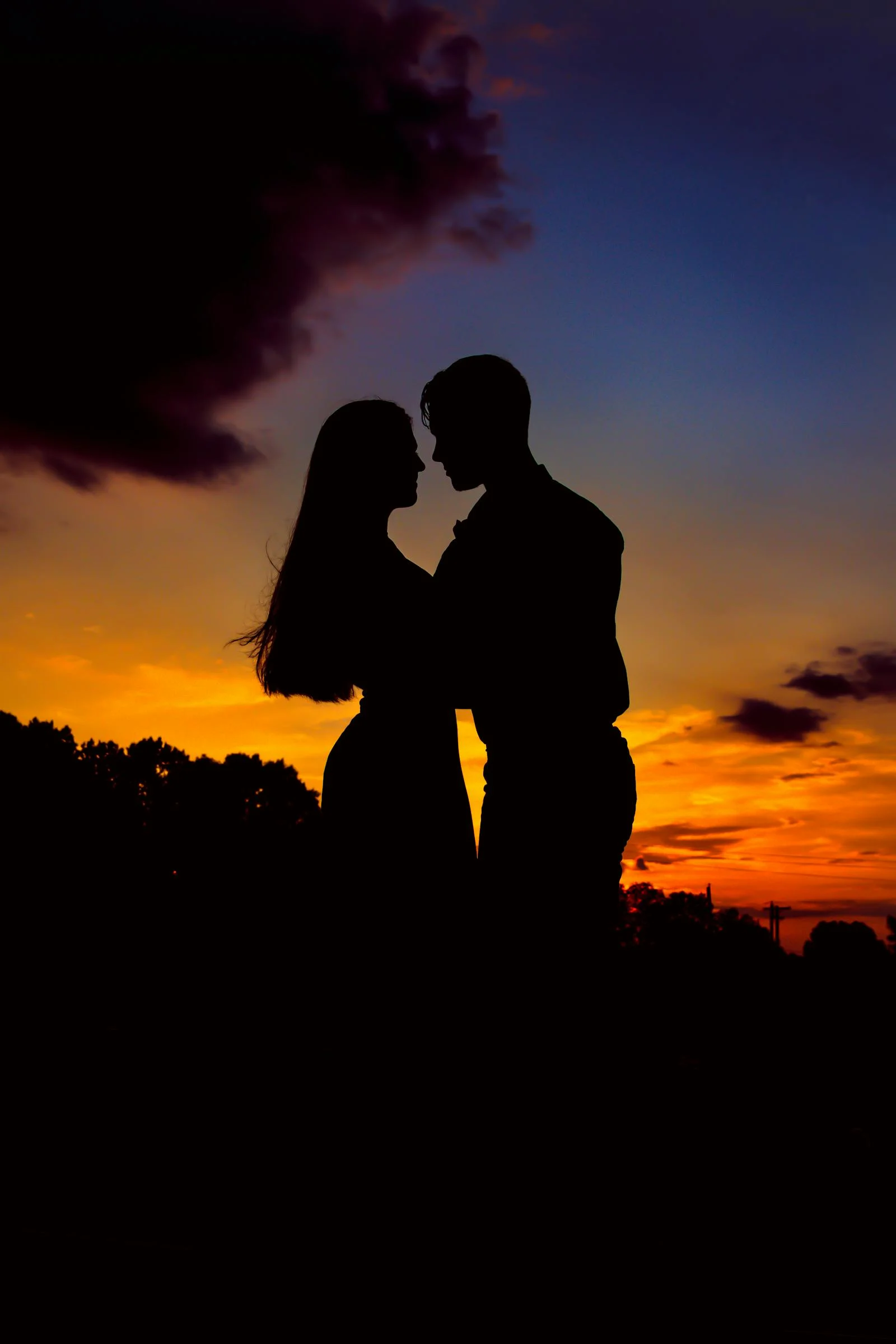 Siluety dvou lidí u západu slunce, držící se za ruce