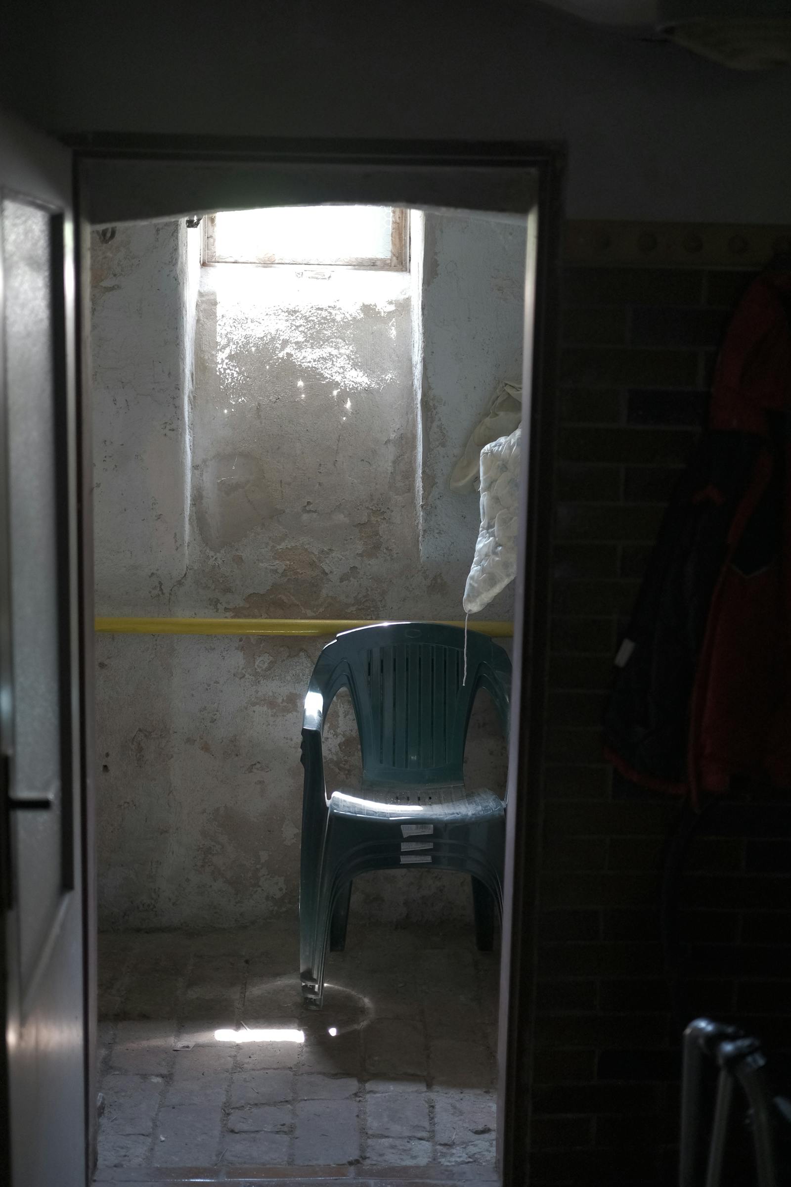 Prázdná dřevěná židle v tlumeném světle u okna