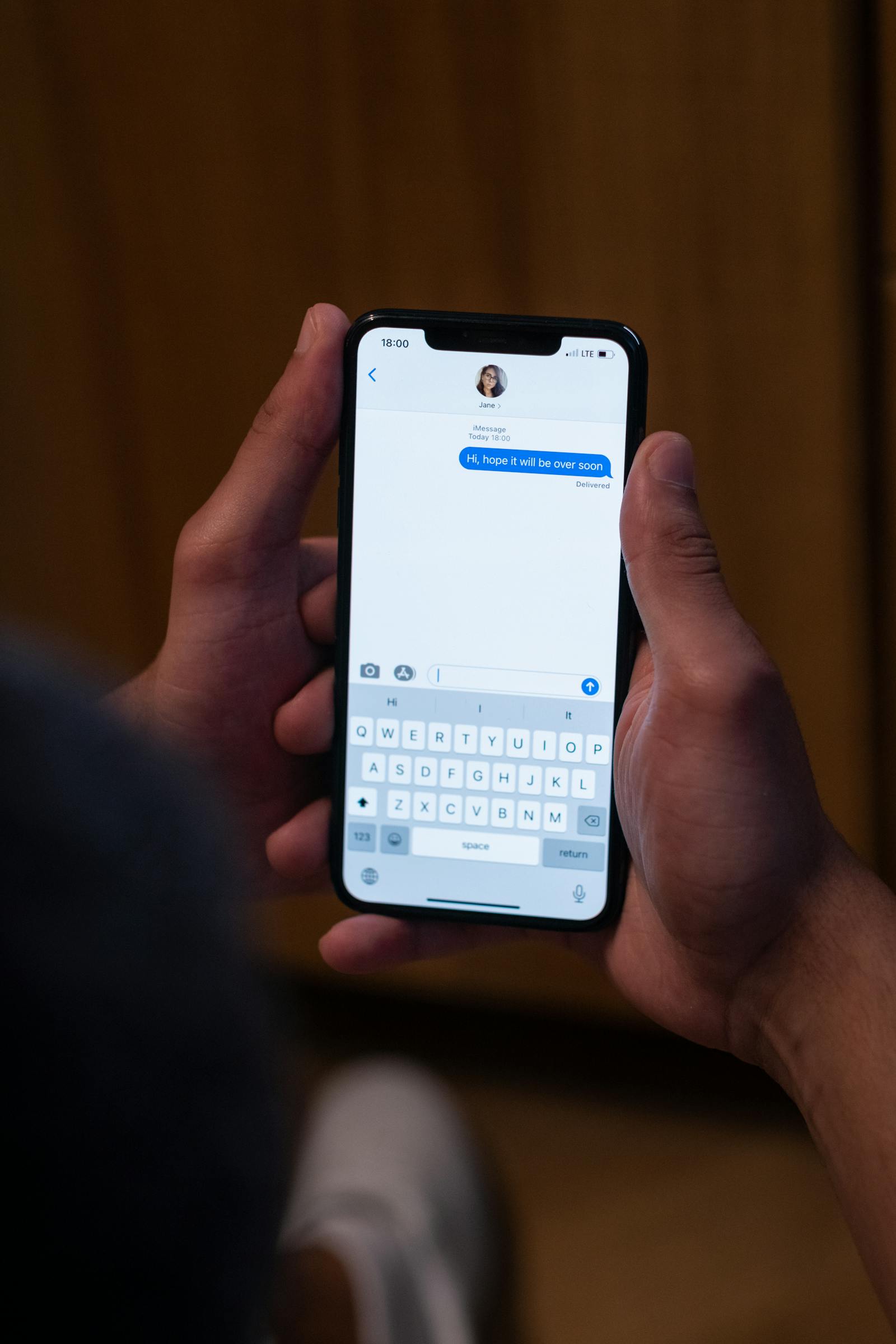 Ruka drží telefon s otevřenou konverzací v aplikaci pro zprávy