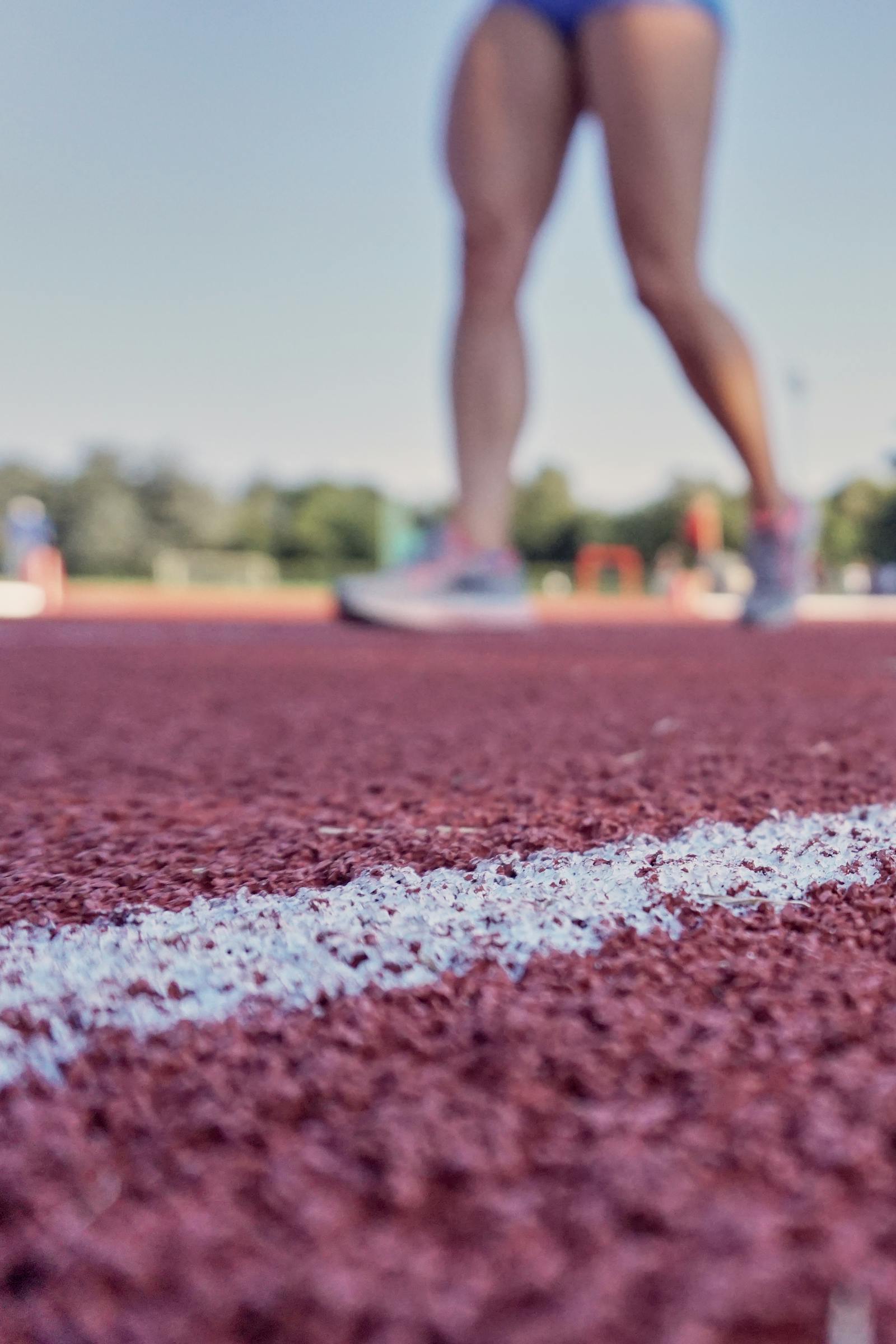 Detail nohou sportovce v běžeckých botách na atletické dráze